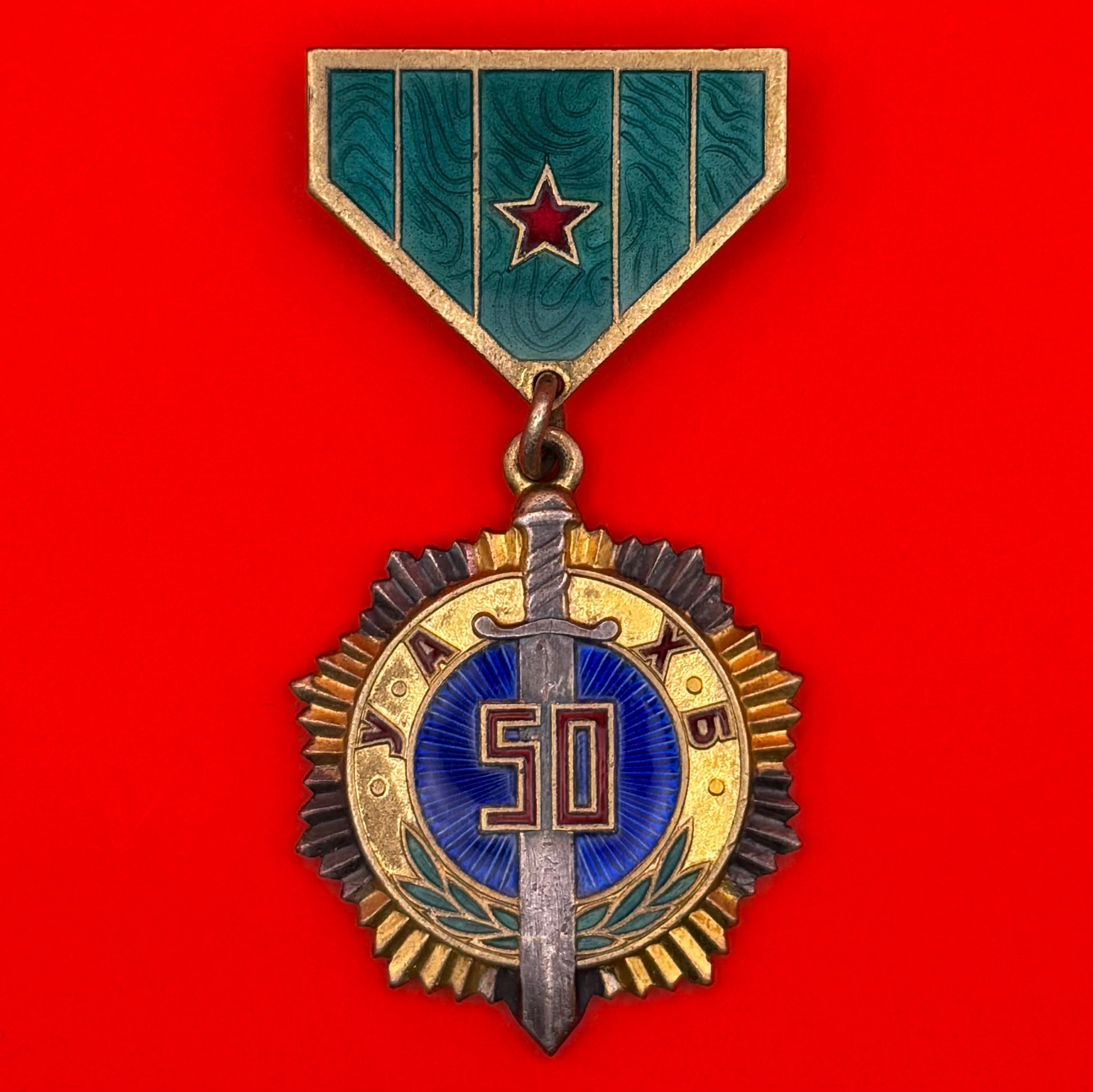 Mongolian State Security 50th Anniversary Medal (1972) featuring a gold and silver ten-pointed star with sword and blue enamel center, suspended from a green ribbon with red star.
