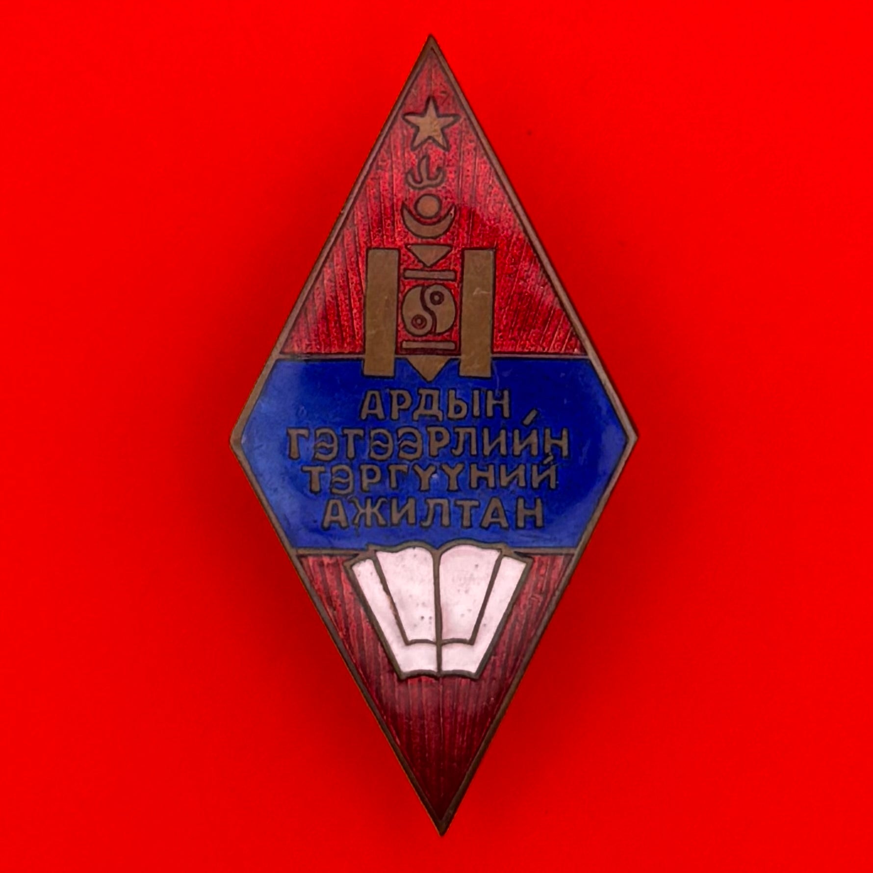 Front view of 1960s Mongolian Enlightenment Employee Badge with red and blue enamel, Pyongyang Mint