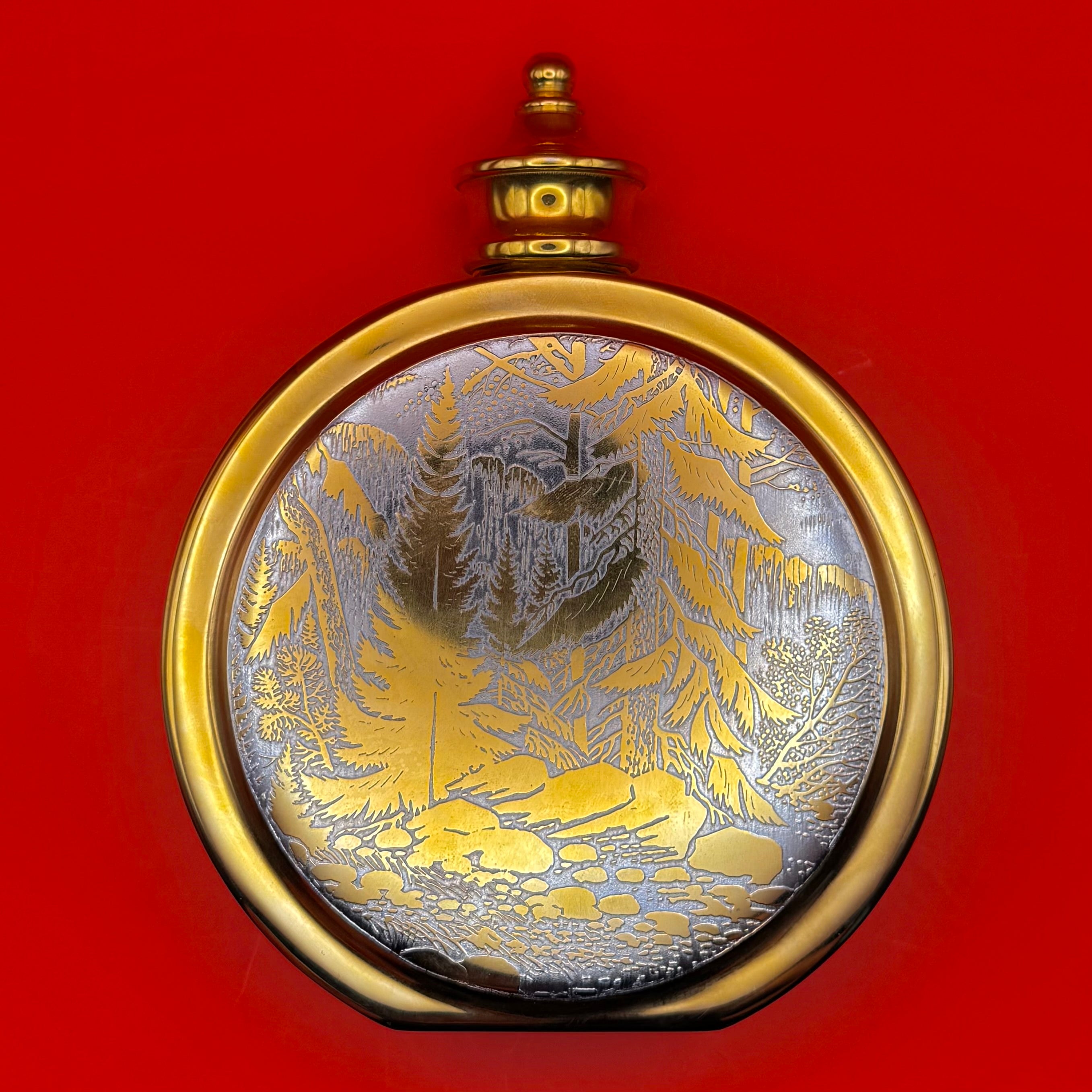 Hand-engraved Russian flask with detailed forest and mountain stream design in gold and silver tones