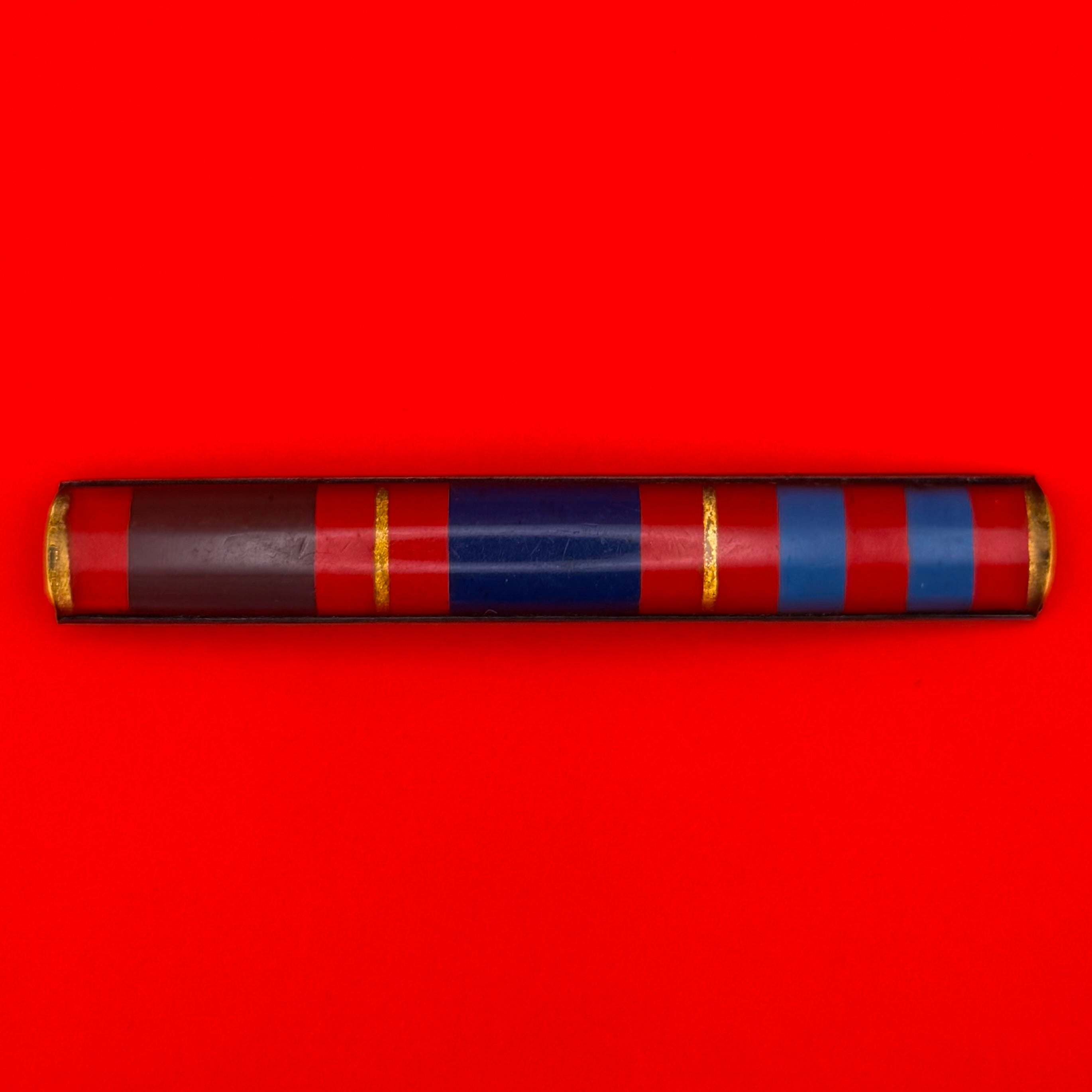 1990s Mongolian military service ribbon bar with vivid red, blue, and gold stripes in vintage metal frame.