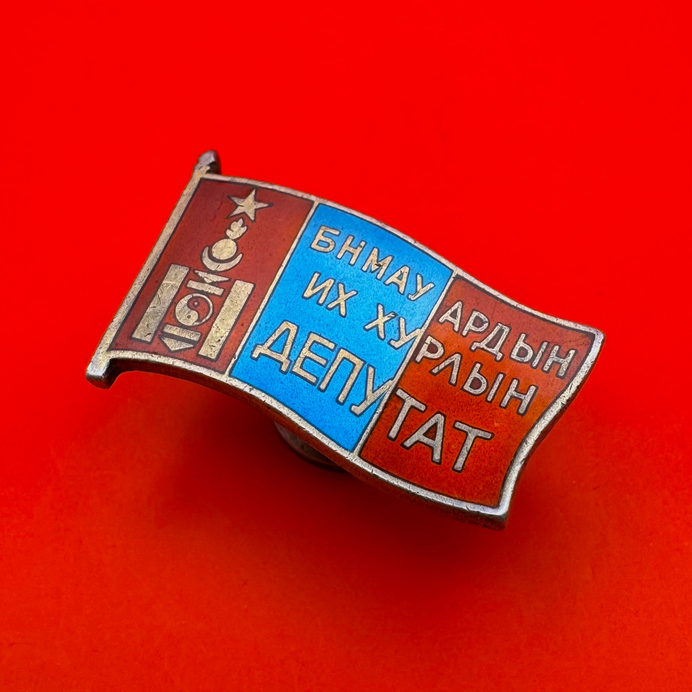 Angled display of rare 1960s Mongolian parliamentary badge highlighting flag-shaped form and depth