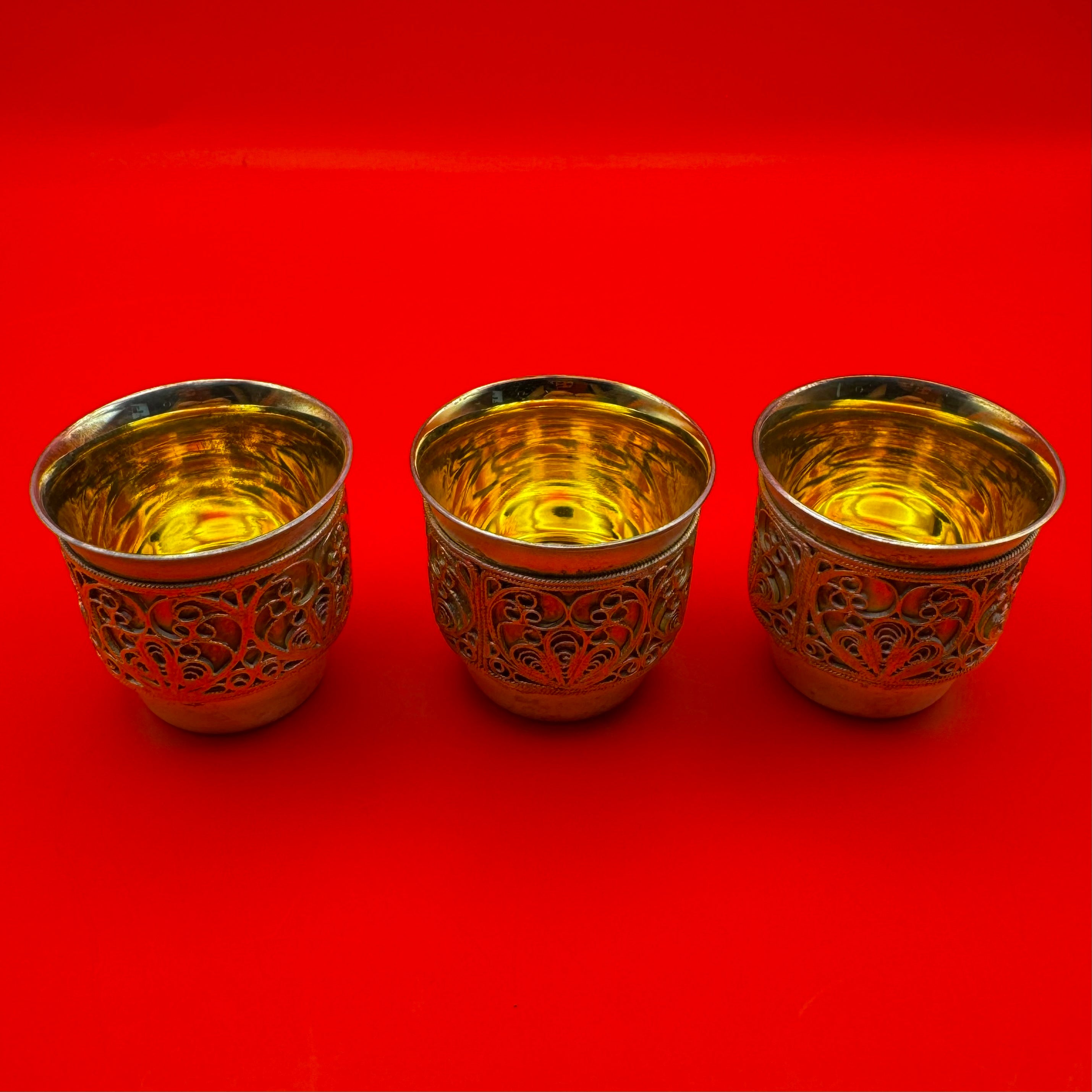 Set of three Russian gold-plated brass shot cups with filigree design included in premium gift set from upper view