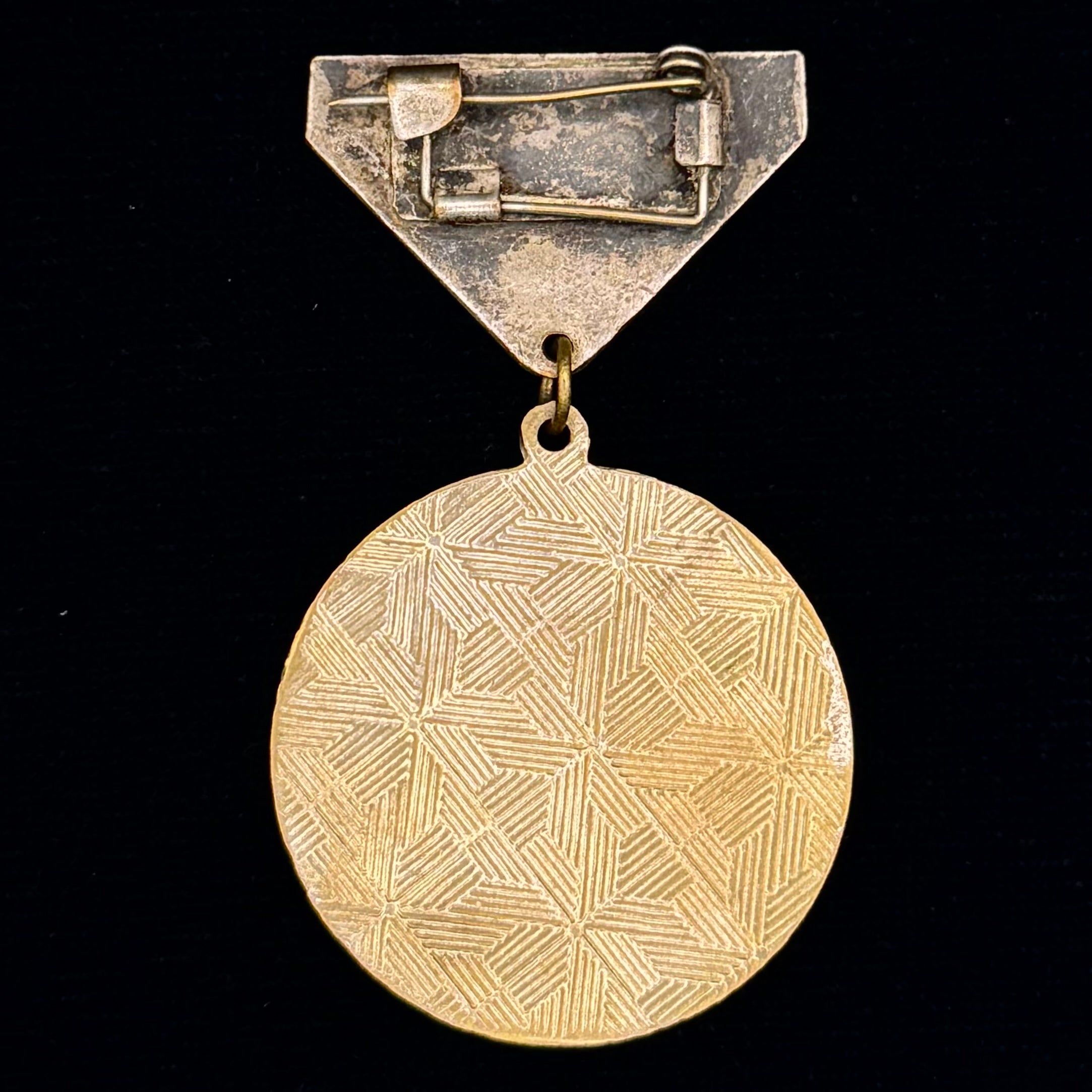 Brass combat medal with geometric design on a black background